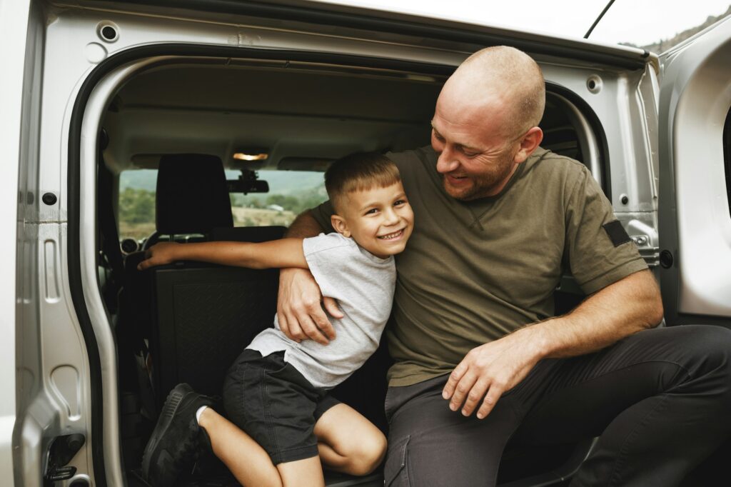 Happy father and son sitting in car trunk