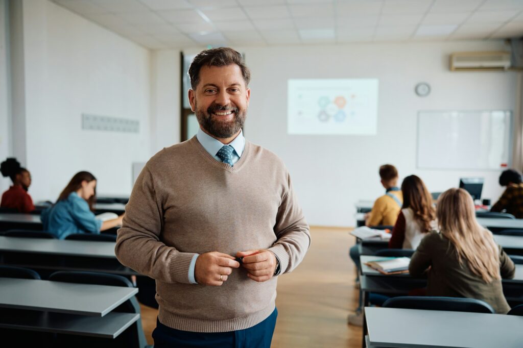 Happy university teacher in the classroom looking at camera.