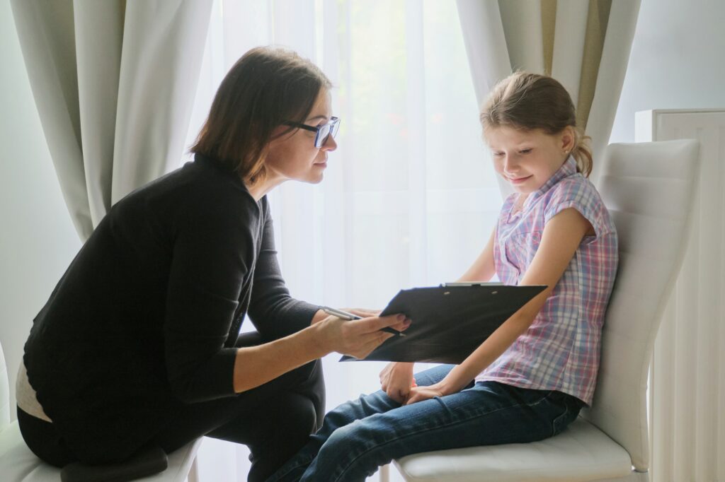 Meeting child girl with school counselor psychotherapist.