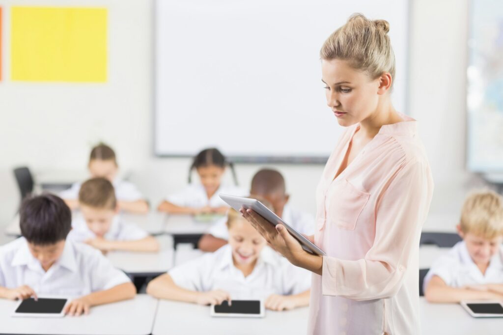 Teacher teaching kids on digital tablet